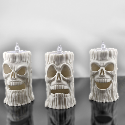 Front view of three white 3D printed skull flameless candle holders by VectorDesignsArizona with different face expressions, LED T-lights on top, gothic Halloween decoration.