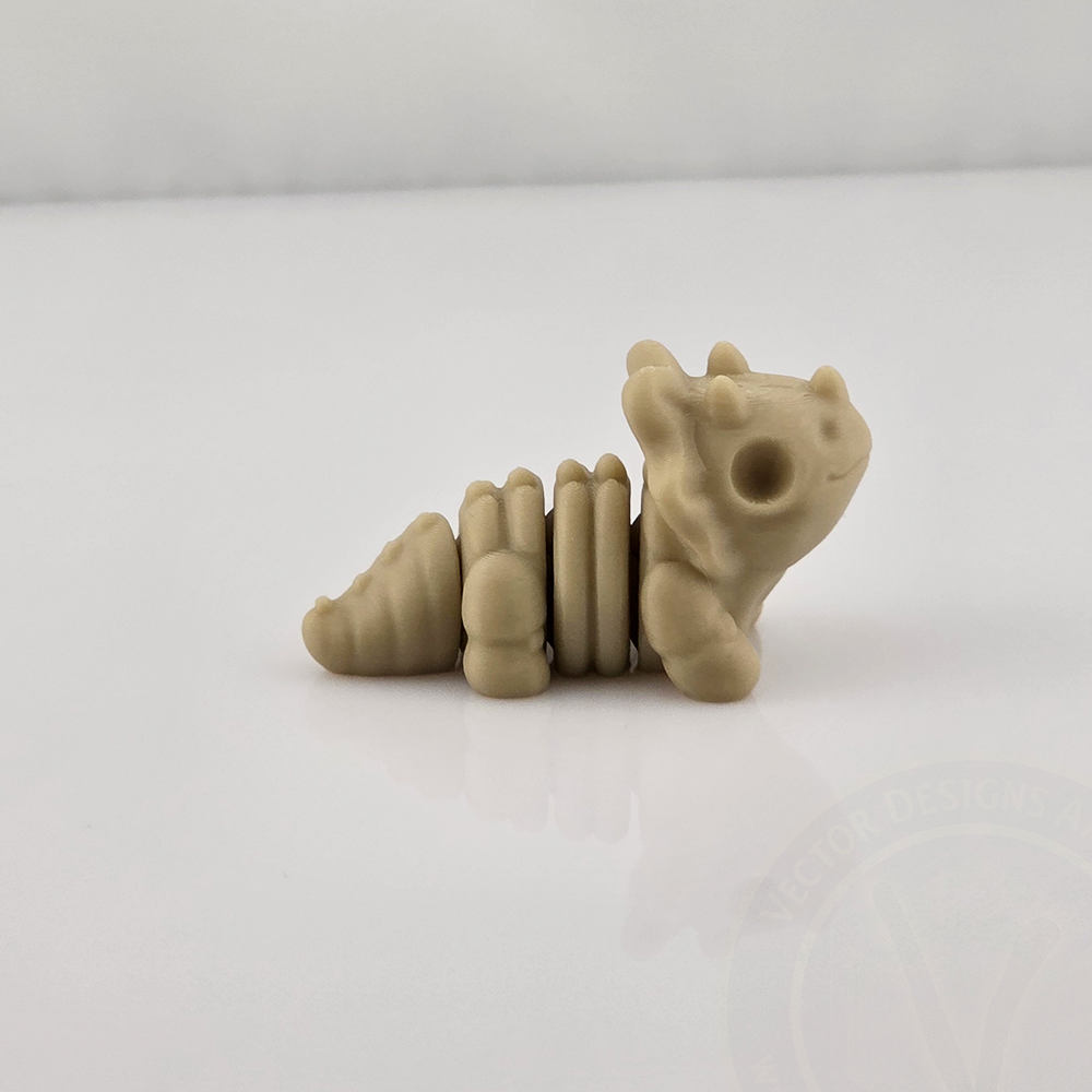 Tan mini flexy dragon toy sitting on glossy white background, side view.