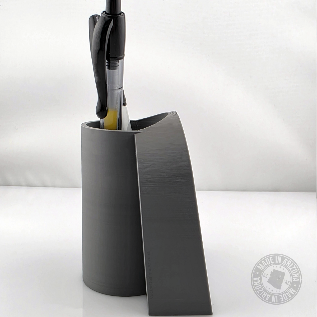 Side view of gray tombstone desk pen holder with pens inserted in top.