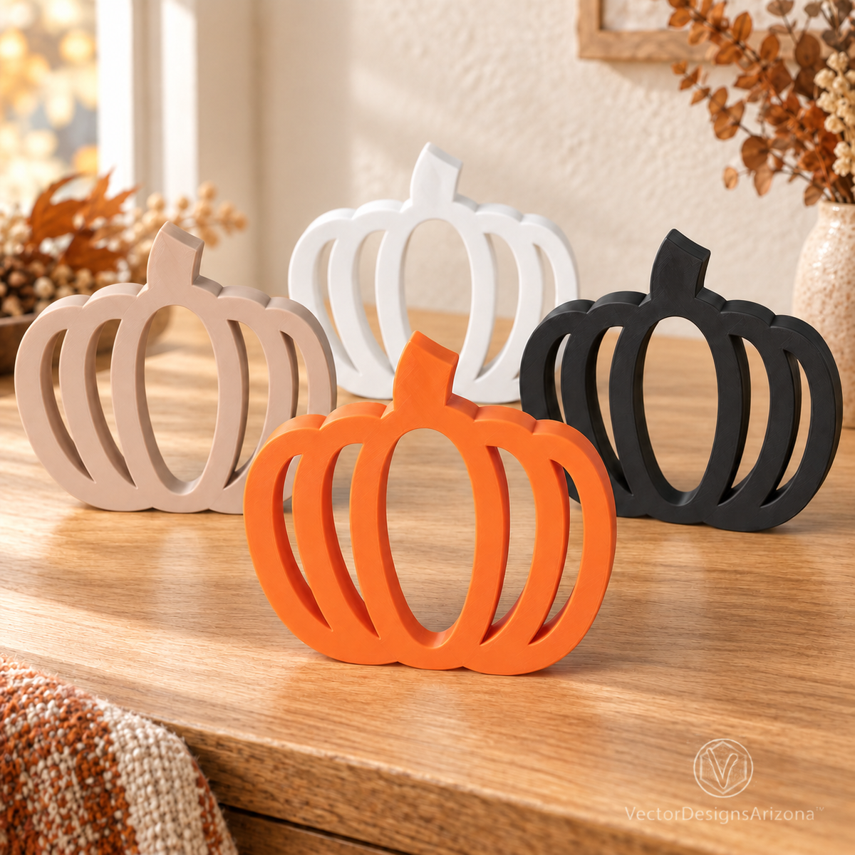 Four minimalist 3D-printed pumpkins in Mandarin orange, latte brown, ivory white, and matte black on a warm autumn console.