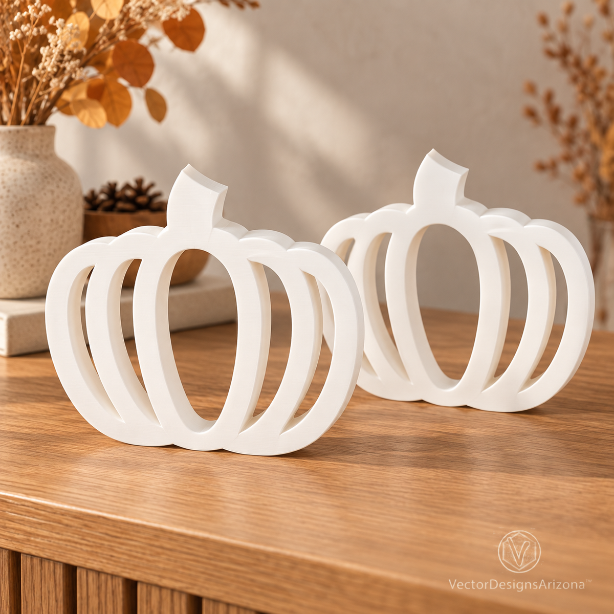 Two ivory white minimalist 3D-printed pumpkins with open-frame designs, styled on a wood console with warm fall decor.