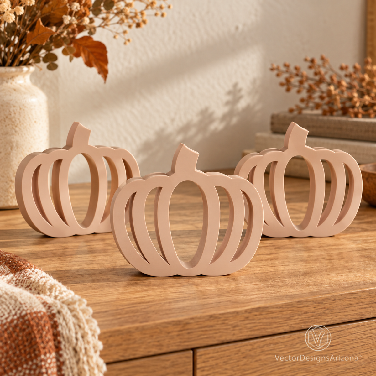 Three beige latte-brown minimalist 3D-printed pumpkins with open-frame designs, styled on a warm autumn console.