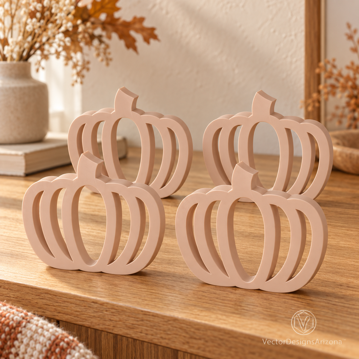 Four beige latte-brown minimalist 3D-printed pumpkins with open-frame designs, styled on a warm autumn console.