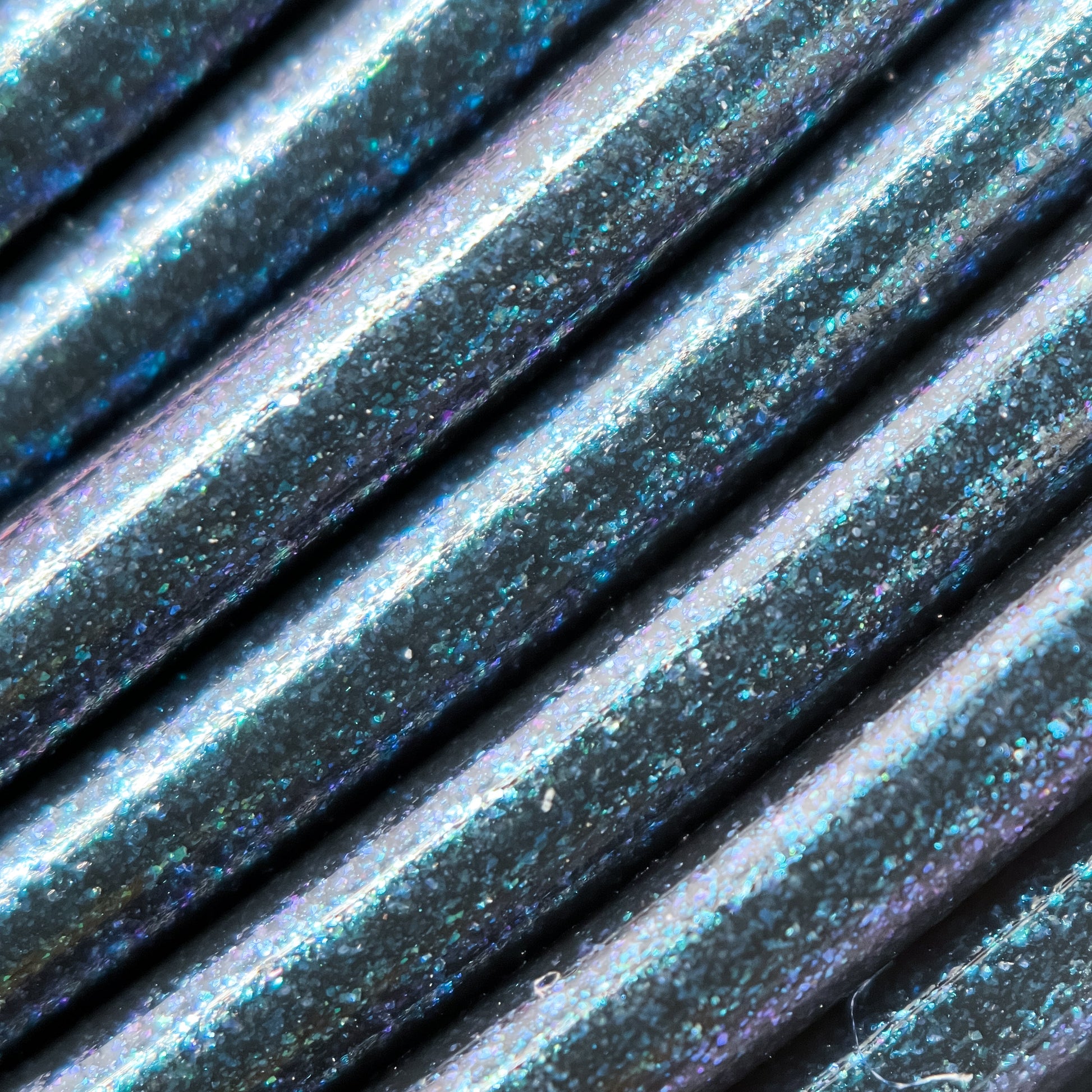 Cookiecad Dark Magic PETG filament close-up – green-blue-purple iridescent shimmer on black base