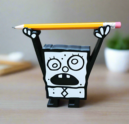 3D printed cartoon-inspired Doodle Bob style pencil holder holding a yellow pencil horizontally across raised arms on a desk
