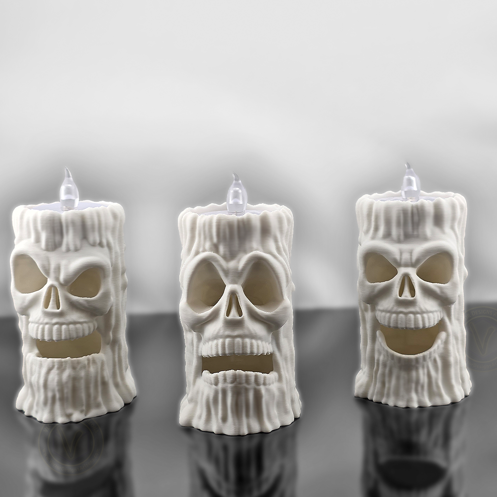 Front view of three white 3D printed skull flameless candle holders by VectorDesignsArizona with different face expressions, LED T-lights on top, gothic Halloween decoration.