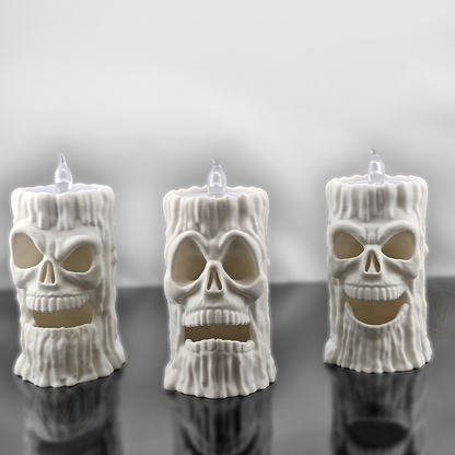 Front view of three white 3D printed skull flameless candle holders by VectorDesignsArizona with different face expressions, LED T-lights on top, gothic Halloween decoration.