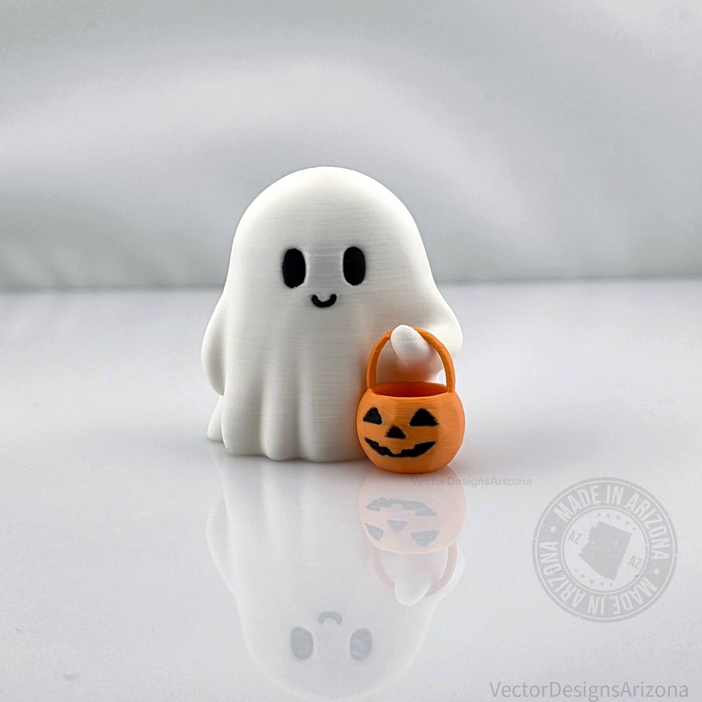 Cute 3D printed ghost figurine holding an orange jack-o’-lantern bucket, handmade Halloween desk or shelf decoration by VectorDesignsArizona.
