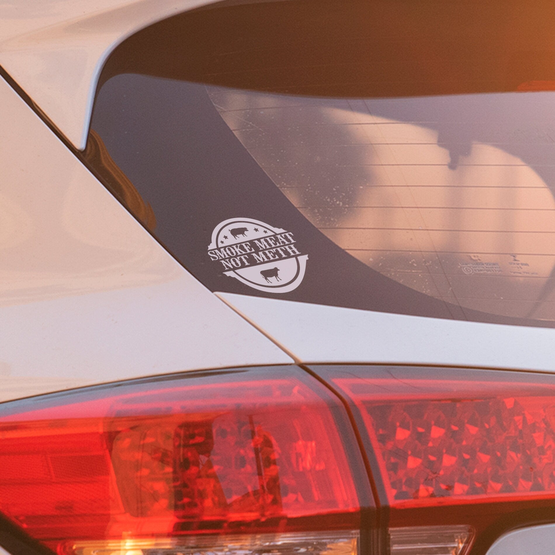 Humorous white vinyl decal with BBQ message ‘Smoke Meat Not Meth’ applied to vehicle window, durable outdoor sticker.