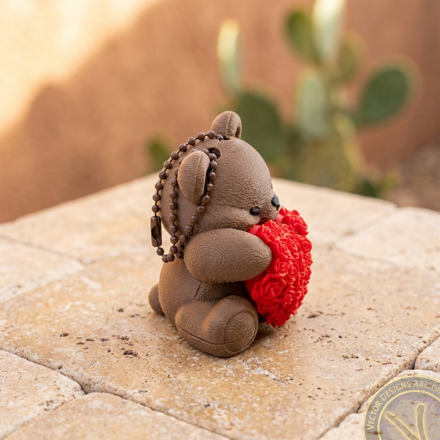 Right side of a brown bear backpack clip with a rose heart, highlighting the secure ball chain attachment mechanism.