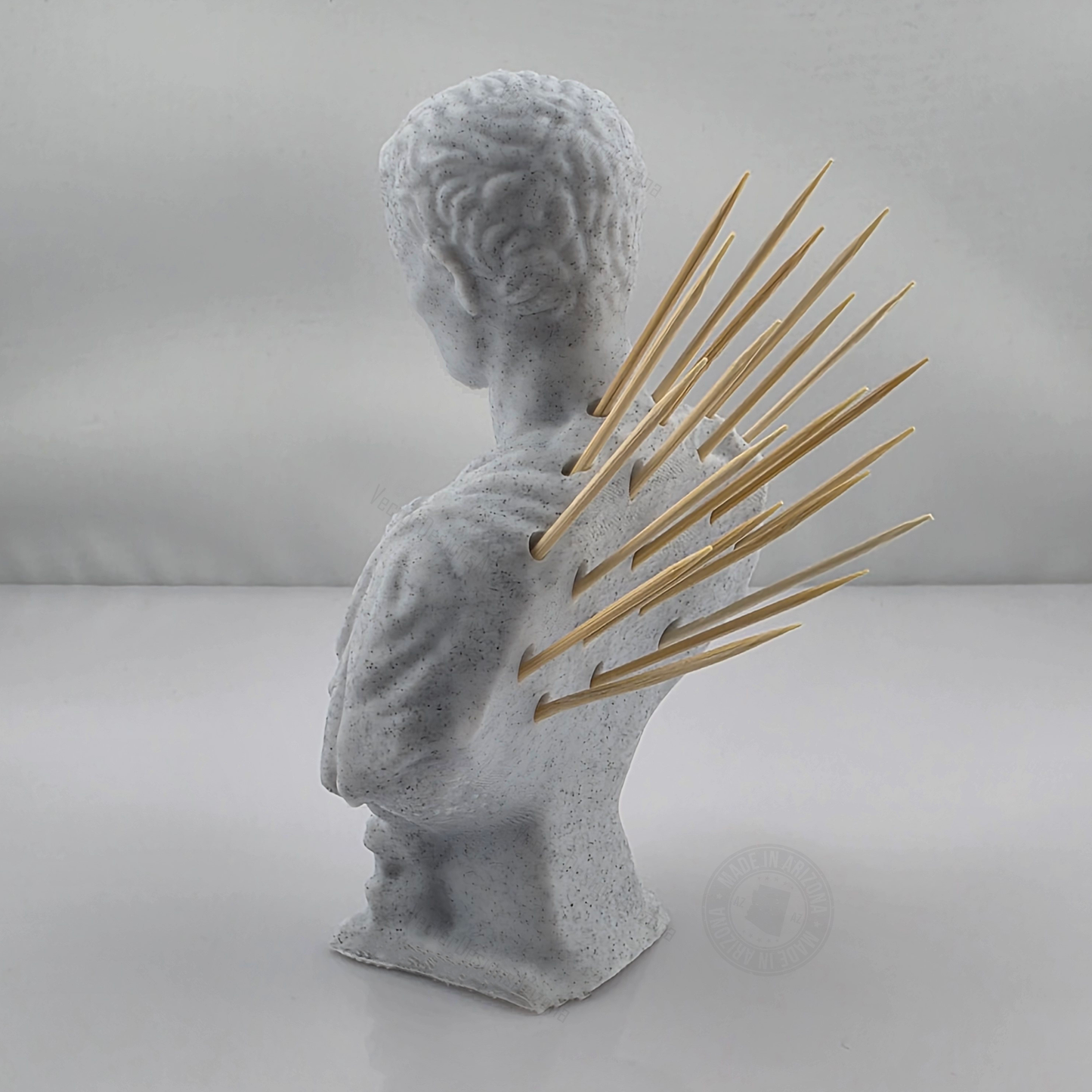 3D printed white marble Caesar bust toothpick holder with wooden toothpicks fanned from the back on a clean studio background