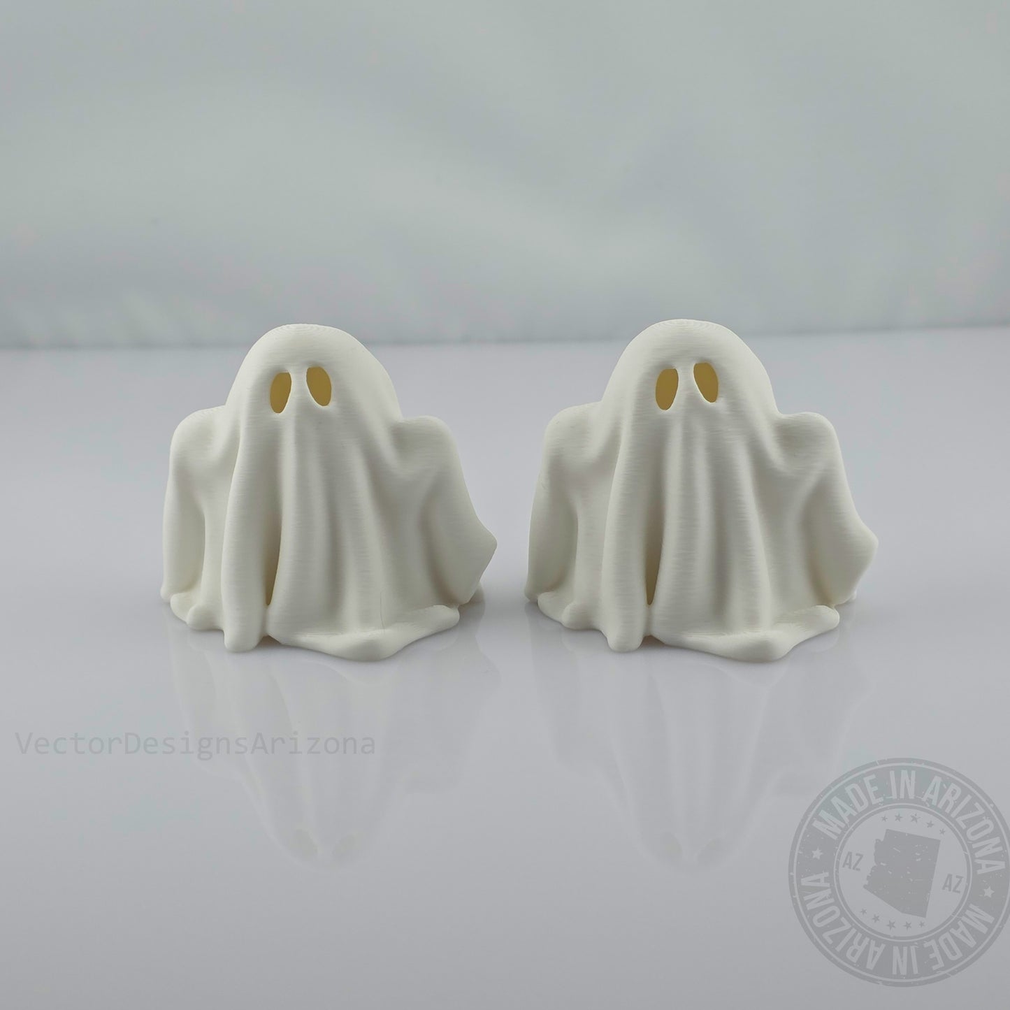Two minimalist white ghost figurines on glossy white background, front view.