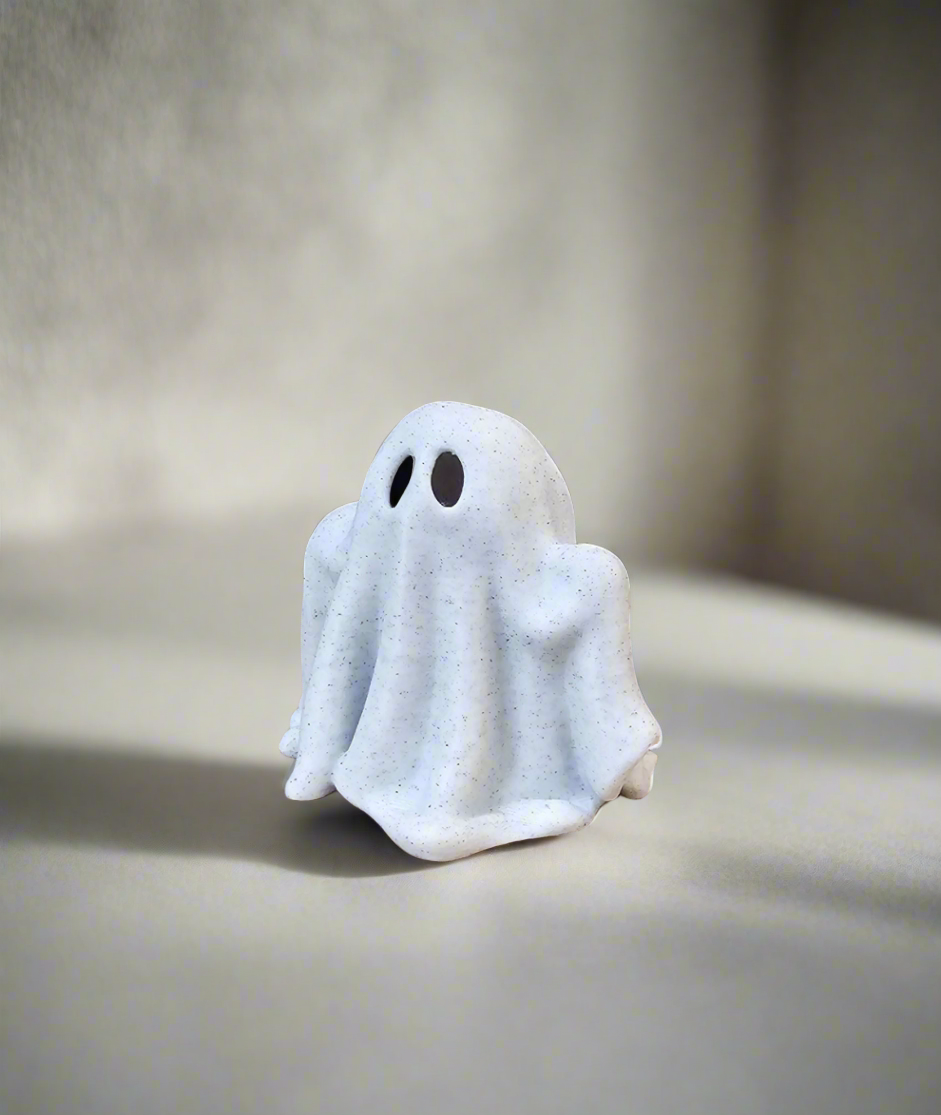 Small elegant ghost figurine on neutral surface with soft shadows and blurred background.