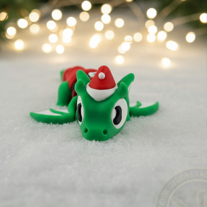 Close-up of a VectorDesignsArizona 3D printed flexi Elf Dragon fidget figurine on snow, styled as cozy Christmas desk décor.