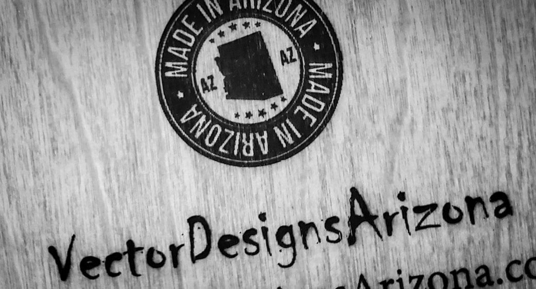 Close-up engraving of Made in Arizona seal and VectorDesignsArizona text on wood.