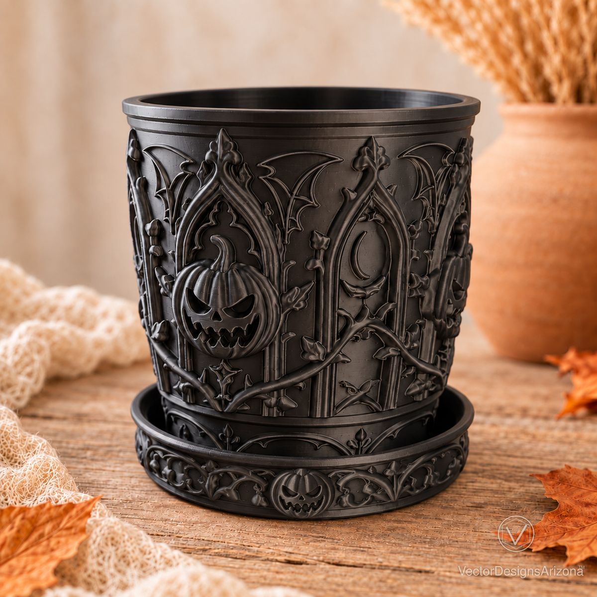 Angled view of the matte black planter showing raised pumpkin, gothic arch and vine details above its saucer.