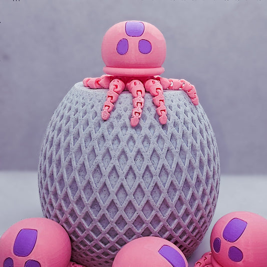 Pink jellyfish flexi fidget toy posed on textured stand with more jellyfish around.