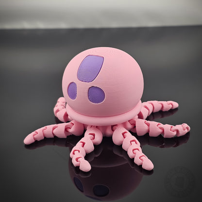 Pink jellyfish flexi fidget toy with tentacles spread out on glossy black surface.