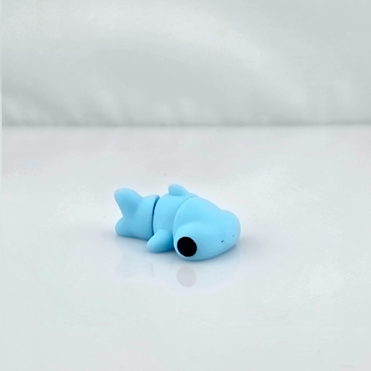 Light blue mini flexy shark toy lying on glossy white background.