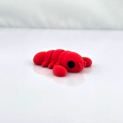 Small red flexy animal figurine lying on glossy white background, side view.