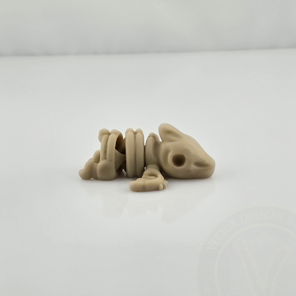 Tan mini flexy skeletal creature toy lying on glossy white background, side view.