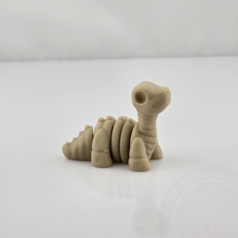 Tan mini flexy skeleton dinosaur toy sitting on glossy white background, side view.