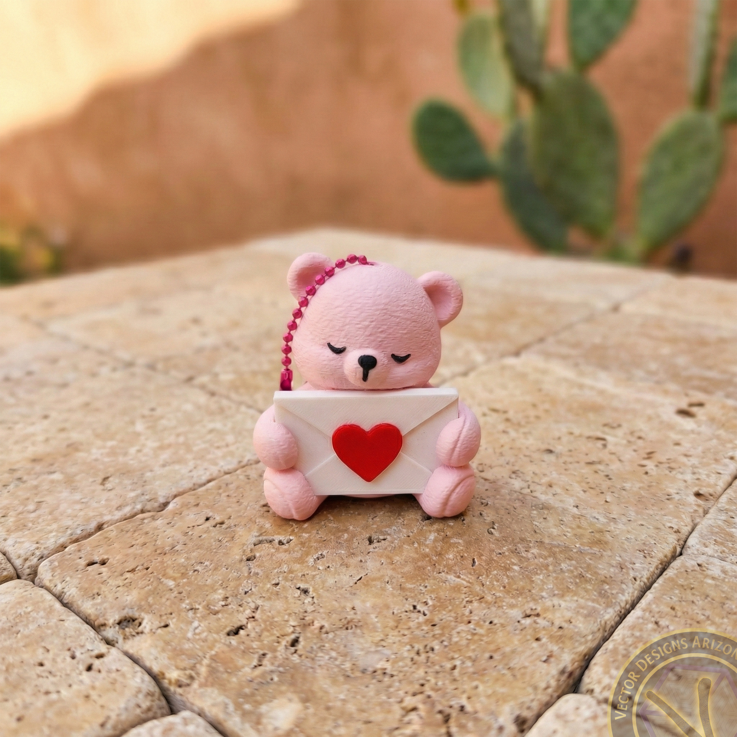 Front view of a pink 3D printed bear bag charm holding a love letter envelope, ideal as a cute backpack clip or zipper pull.