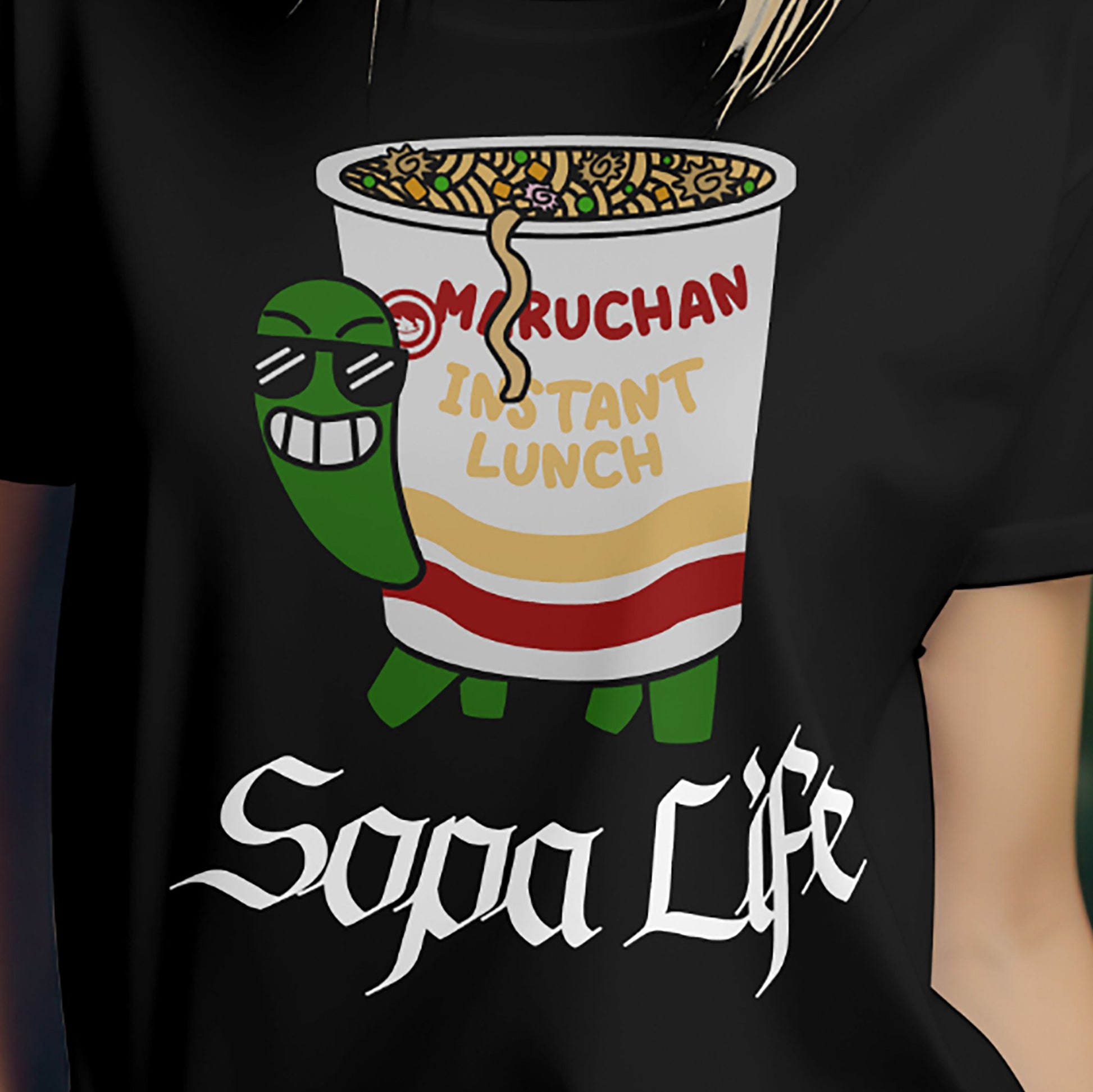 Person wearing black ramen turtle Sopa Life T-shirt with cartoon noodle cup design.
