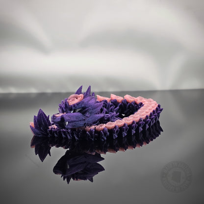 Purple rose dragon flexi figurine coiled on glossy black surface with reflection.
