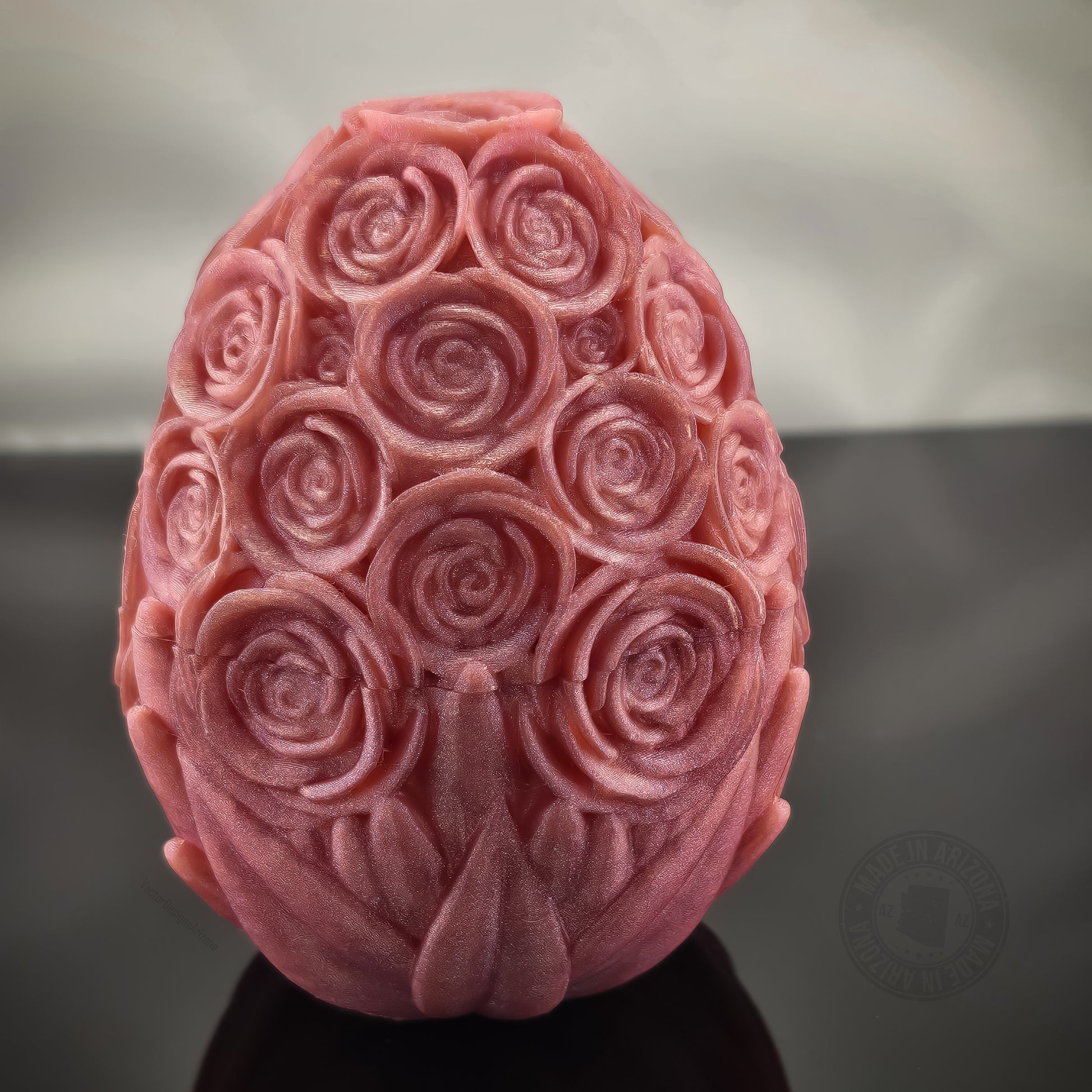 Pink rose-textured dragon egg figurine standing on glossy black surface, front view.