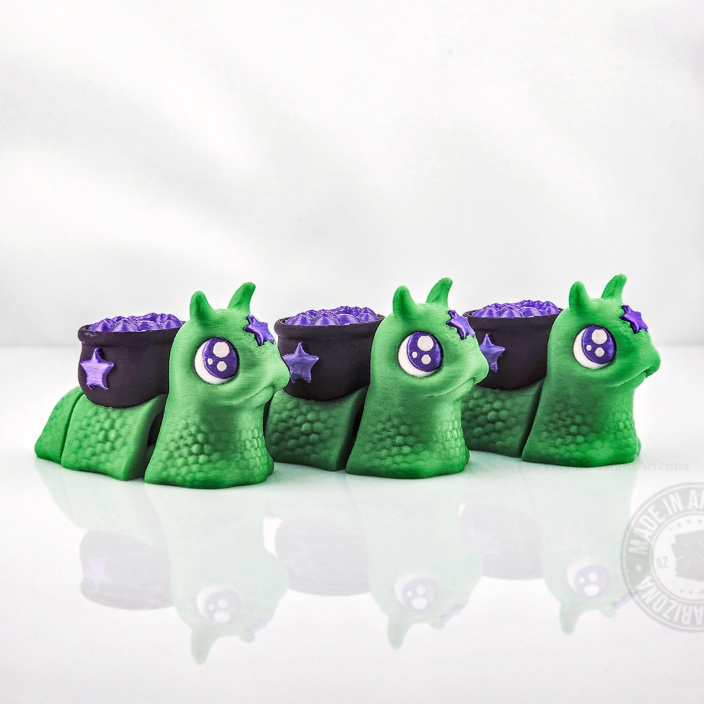 Row of green spooky snails with purple cauldron shells and stars on white background.