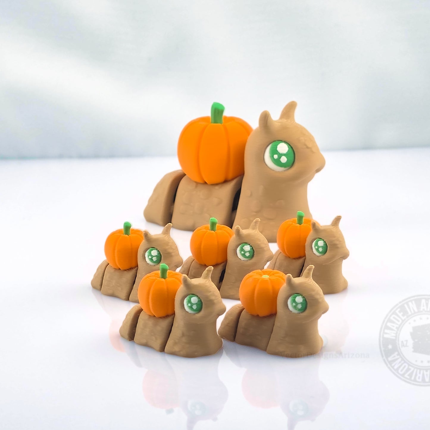 Large pumpkin spooky snail with several smaller pumpkin snails on white reflective background.