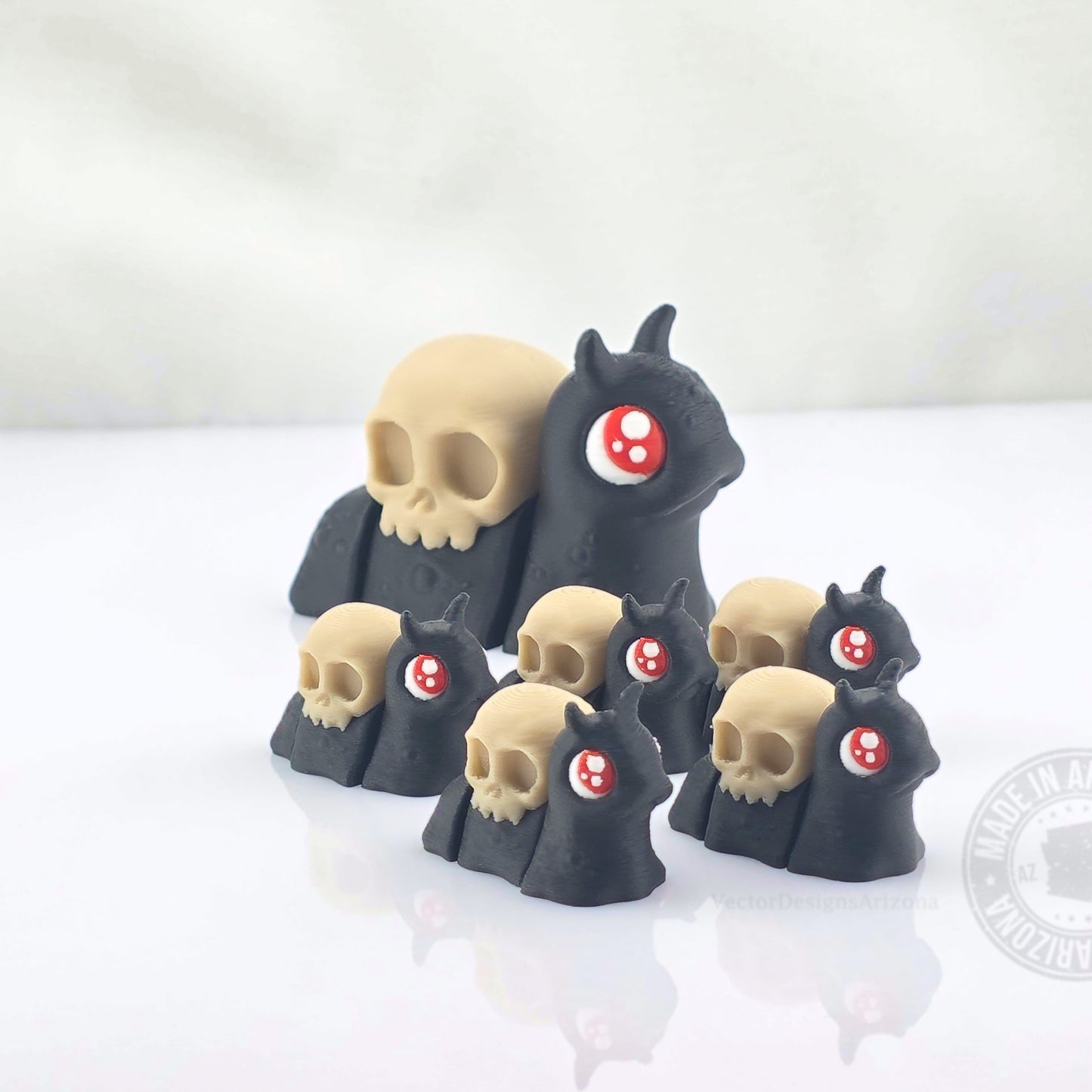 Large skull spooky snail surrounded by smaller matching snails on white reflective background.