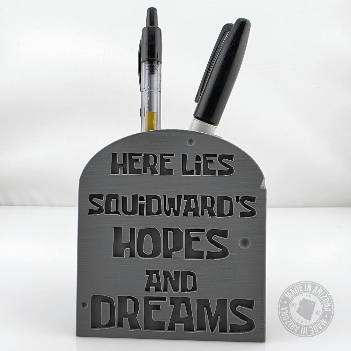 Gray tombstone desk pen holder with Squid-ward’s hopes and dreams engraved text.